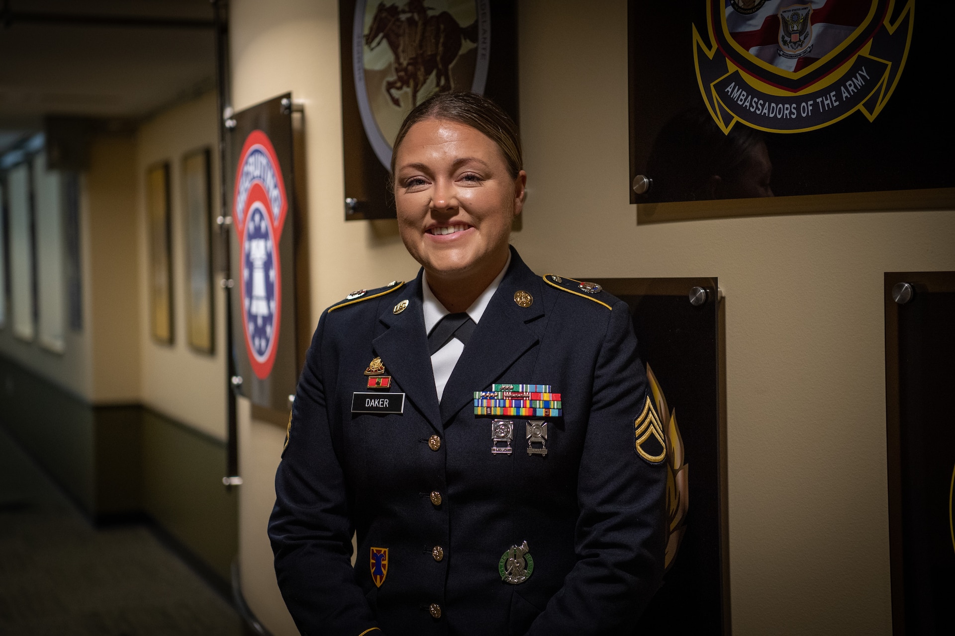 a woman wearing a u.s. army uniform stands in a hallway