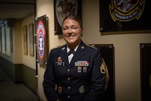 a woman wearing a u.s. army uniform stands in a hallway