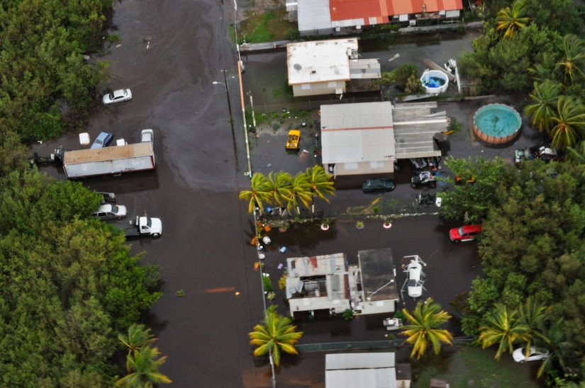 An aerial view of several homes and vehicles that were damaged during a hurricane.