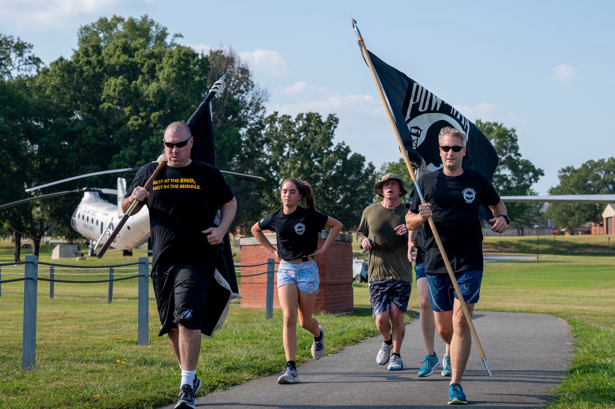 A group of people running. two people on either side of the group carry a flag