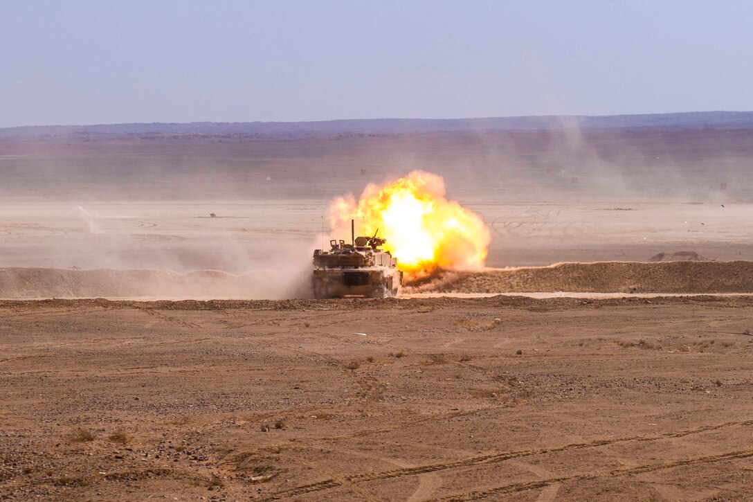 A tank fires in a desert area.