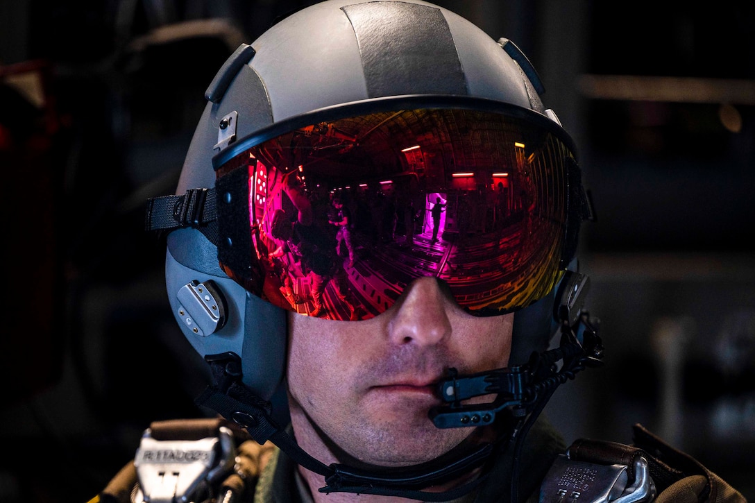 A closeup of an airman wearing a helmet with a reflective visor.