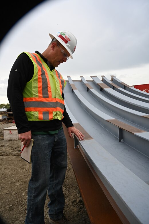 Civil engineer reviews paint covering on a Tainter gate at a construction site.