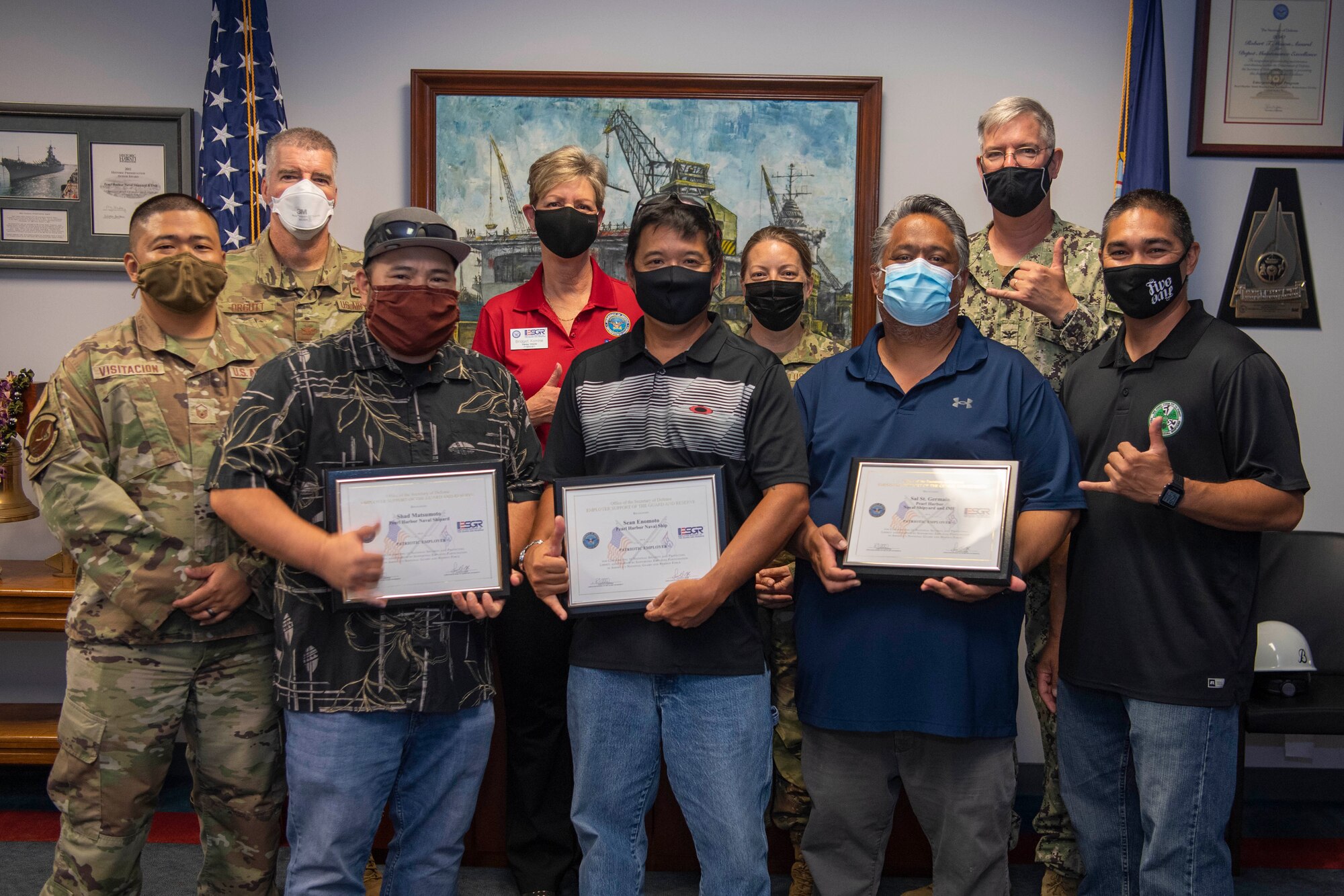 A group of people, civilian and military, standing together with certificates of appreciation.