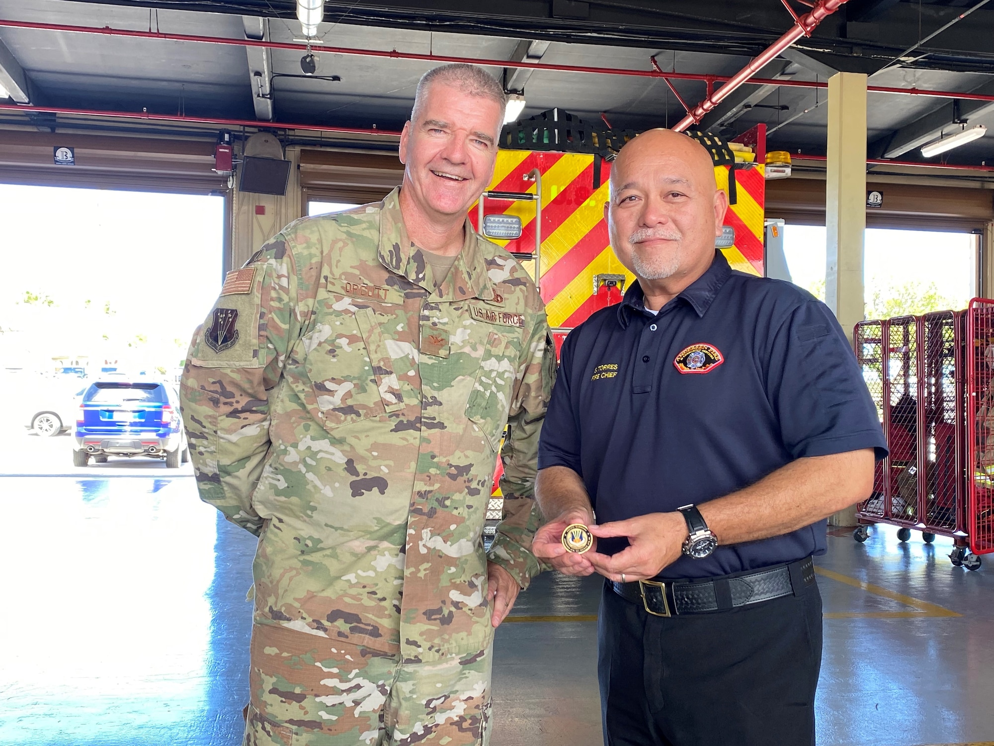 Col. Joseph Orcutt stands with Fire Chief Stanley Torres, who showcases challenge coin.