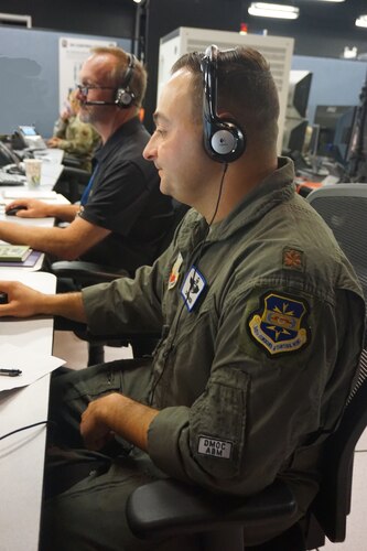 photo of US Military members sitting wearing headsets at computers