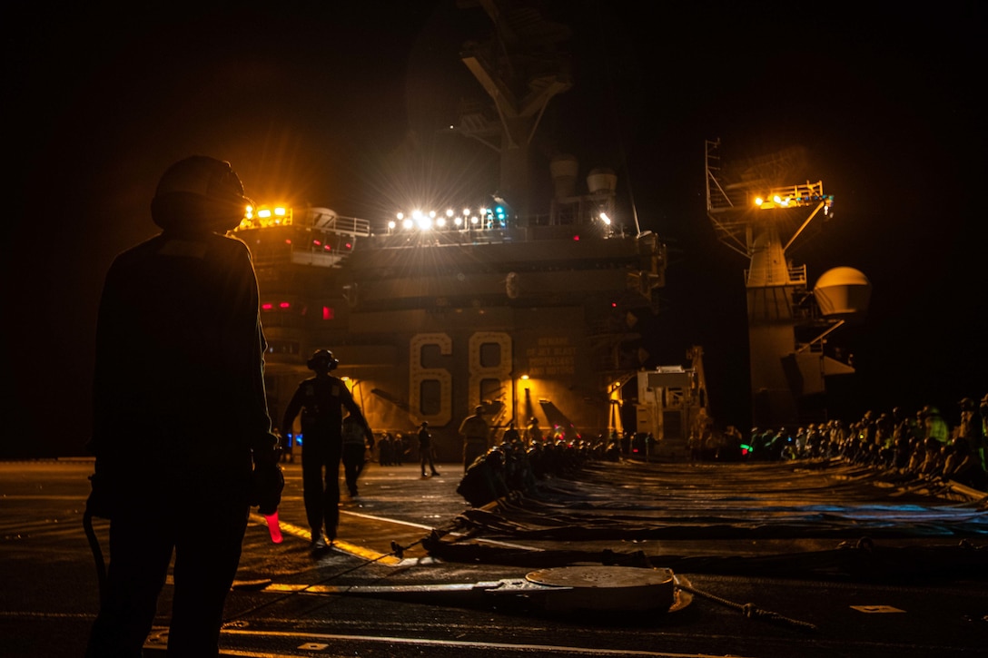 Sailors conduct a night drill aboard an aircraft carrier.