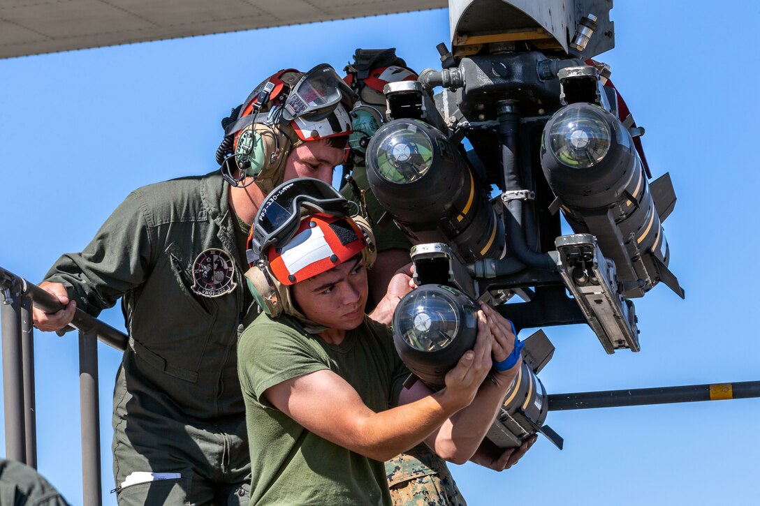 Marines place missiles on an aircraft.
