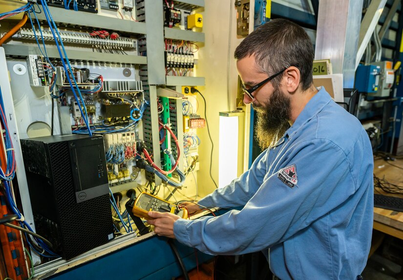 Photo of Gregory Kipp testing equipment with a multimeter