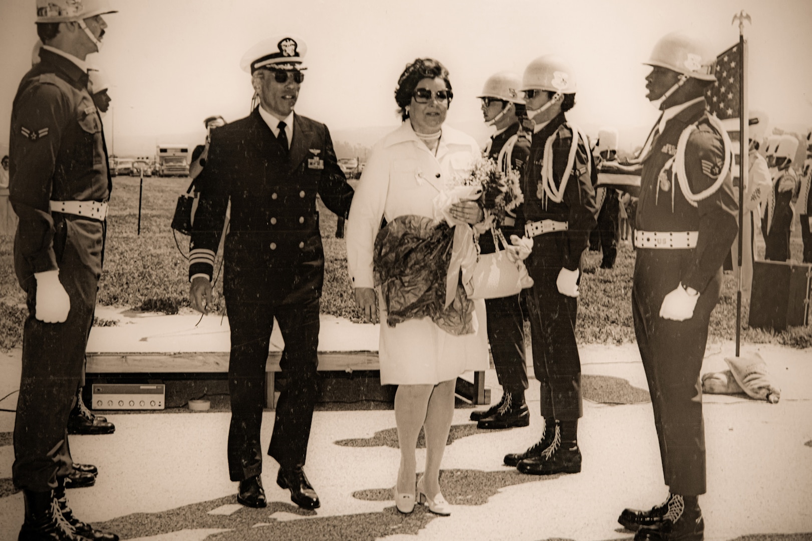 Male and female walk between 5 male soldiers