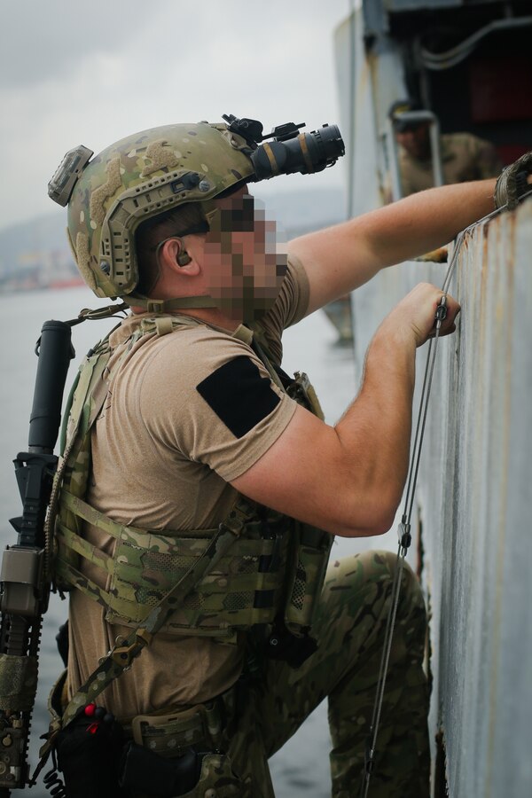 A U.S. Sailor assigned to a Navy SEAL Team, climbs up a ladder during Visit, Board, Search, and Seizure (VBSS) training with partner nations during exercise UNITAS LXIII in Rio de Janeiro, Sept. 15, 2022. UNITAS is the world’s longest-running annual multinational maritime exercise that focuses on enhancing interoperability among multiple nations and joint forces during littoral and amphibious operations in order to build on existing regional partnerships and create new enduring relationships that promote peace, stability, and prosperity in the U.S. Southern Command’s area of responsibility. (U.S. Marine Corps photo by Cpl. Ethan Craw) (This photo has been altered for security purposes by blurring faces and tattoos)