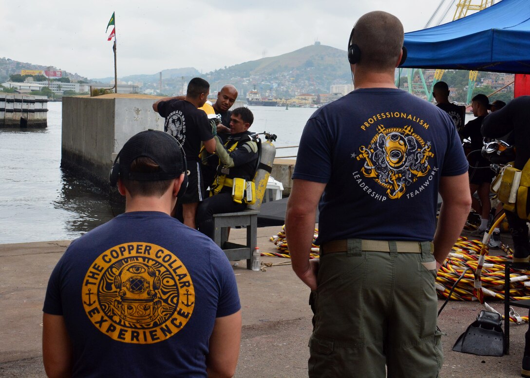 RIO DE JANEIRO – U.S. Navy divers, assigned to Mobile Diving and Salvage Unit 2 (MDSU-2) watch as their Brazilian counterparts get ready for a dive during UNITAS LXIII, Sept. 14, 2022. UNITAS is the world’s longest-running maritime exercise. Hosted this year by Brazil, it brings together multinational forces from Belize, Brazil, Cameroon, Chile, Colombia, Dominican Republic, Ecuador, France, Guyana, Jamaica, Mexico, Namibia, Panama, Paraguay, Peru, South Korea, Spain, United Kingdom, Uruguay, and the United States conducting operations in and off the coast of Rio de Janeiro. The exercise trains forces to conduct joint maritime operations through the execution of anti-surface, anti-submarine, anti-air, amphibious and electronic warfare operations that enhance warfighting proficiency and increase interoperability among participating naval and marine forces. (U.S. Navy photo by Mass Communication Specialist 3rd Class Jahlena Royer/Released)