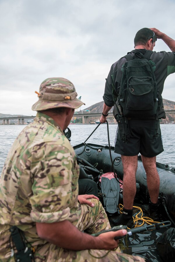 A Brazilian service member with the Grupamento de Mergulhadores de Comabte, Marinha do Brasil (Brazilian Navy Combat Divers Group), and a U.S. Navy SEAL assigned to a Naval Special Operations Team, watch the water during a dive mission as part of exercise UNITAS LXIII in Rio de Janeiro, Sept. 12, 2022. UNITAS is the world's longest-running annual multinational maritime exercise that focuses on enhancing interoperability among multiple nations and joint forces during littoral and amphibious operations in order to build on existing regional partnerships and create new enduring relationships that promote peace, stability, and prosperity in the U.S. Southern Command’s area of responsibility. (U.S. Marine Corps photo by Sgt. Camila Melendez)
