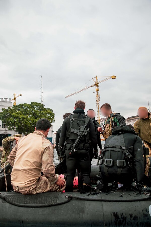Service members from Brazil with the Grupamento de Mergulhadores de Comabte, Marinha do Brasil (Brazilian Navy Combat Divers Group), Hombres Ranas de Infantería de Marina de Ecuador (Ecuadorian Marine Corps Frogmen), Las Fuerzas de Operaciones Especiales de la Marina de Guerra del Perú (The Special Operations Forces of the Peruvian Navy), and U.S. Navy SEALs assigned to a Naval Special Operations Team, converse after completing a dive mission during exercise UNITAS LXIII in Rio de Janeiro, Sept. 12, 2022. UNITAS is the world's longest-running annual multinational maritime exercise that focuses on enhancing interoperability among multiple nations and joint forces during littoral and amphibious operations in order to build on existing regional partnerships and create new enduring relationships that promote peace, stability, and prosperity in the U.S. Southern Command’s area of responsibility. (U.S. Marine Corps photo by Sgt. Camila Melendez) (This photo has been altered for security purposes by blurring faces and tattoos)