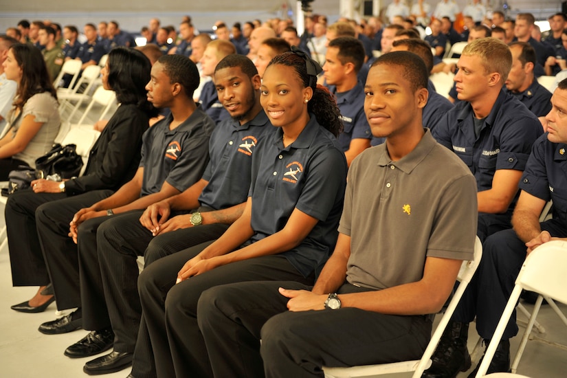 Students sit in an audience and smile.