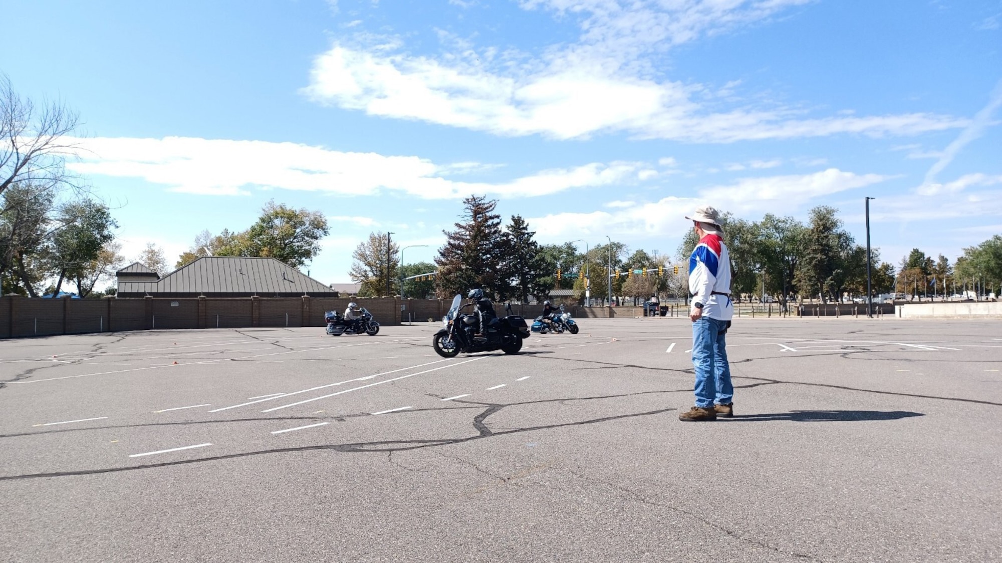 Jim Rosenthal stands watching three motorcycle riders riding in a circle.