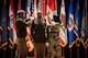 man wearing u.s. army uniform standing on a stage while two people pin a star on each shoulder.