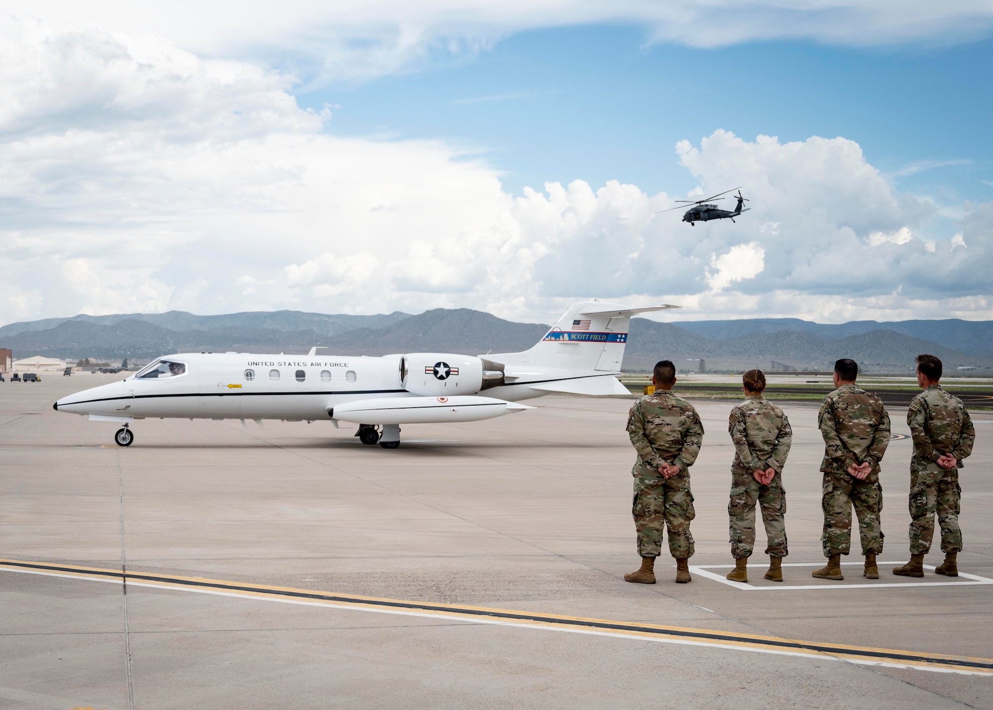 Four Airmen in uniform face a plane