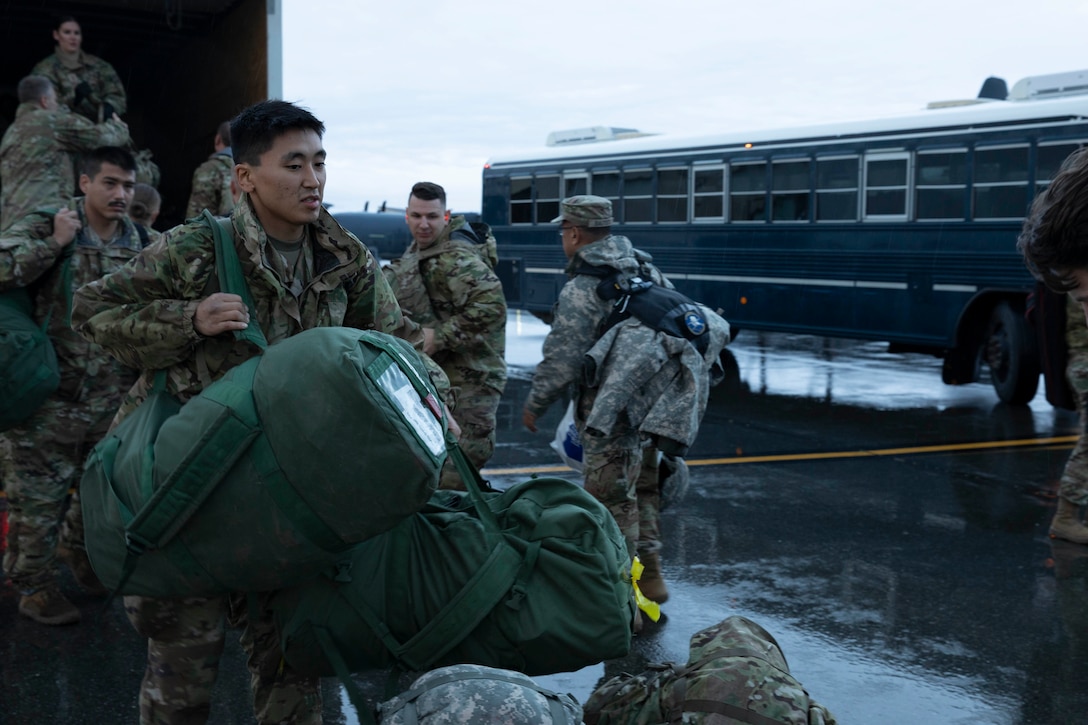 Soldiers of the Alaska Army National Guard transfer their luggage prior to boarding a HC-130 Combat King II for transport to Bethel, Alaska, Sept. 21, 2022. Approximately 100 members of the Alaska Organized Militia, which is comprised of the Alaska National Guard, Alaska State Defense Force and Alaska Naval Militia, were activated following a disaster declaration issued Sept. 17 after the remnants of Typhoon Merbok caused dramatic flooding across more than 1,000 miles of Alaskan coastline. (Alaska National Guard photo by Victoria Granado)