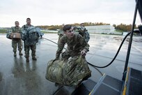 Soldiers of the Alaska Army National Guard transfer their luggage prior to boarding a HC-130 Combat King II for transport to Bethel, Alaska, Sept. 21, 2022. Approximately 100 members of the Alaska Organized Militia, which is comprised of the Alaska National Guard, Alaska State Defense Force and Alaska Naval Militia, were activated following a disaster declaration issued Sept. 17 after the remnants of Typhoon Merbok caused dramatic flooding across more than 1,000 miles of Alaskan coastline. (Alaska National Guard photo by Victoria Granado)