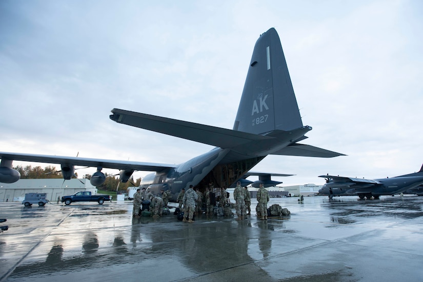 Soldiers of the Alaska Army National Guard transfer their luggage prior to boarding a HC-130 Combat King II for transport to Bethel, Alaska, Sept. 21, 2022. Approximately 100 members of the Alaska Organized Militia, which is comprised of the Alaska National Guard, Alaska State Defense Force and Alaska Naval Militia, were activated following a disaster declaration issued Sept. 17 after the remnants of Typhoon Merbok caused dramatic flooding across more than 1,000 miles of Alaskan coastline. (Alaska National Guard photo by Victoria Granado)