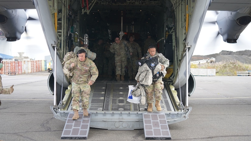 Alaska Army National Spc. Mark Ibay, a petroleum supply specialist with E Company, 1st Battalion, 207th Aviation, left, and Sgt. Maj. Arturo Bautista, operations sergeant major with 38th Troop Command and noncommissioned officer in charge of Joint Task Force – Bethel, exit an HC-130J Combat King II aircraft from the 176th Wing’s 211th Rescue Squadron after arriving in Bethel for disaster relief response Sept. 21, 2022. Approximately 100 service members from the Alaska National Guard, Alaska State Defense Force and Alaska Naval Militia were activated following a disaster declaration issued Sept. 17 after the remnants of Typhoon Merbok caused dramatic flooding across more than 1,000 miles of Alaskan coastline. A JTF in Nome is standing up concurrently as part of Operation Merbok Response. (Alaska National Guard photo by Dana Rosso)