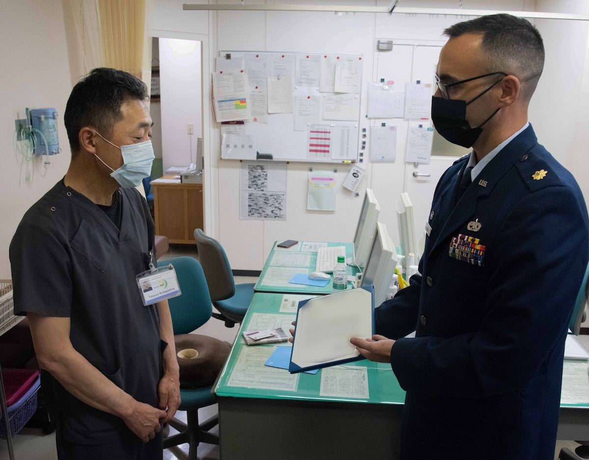 A military member presents an appreciation letter to a doctor