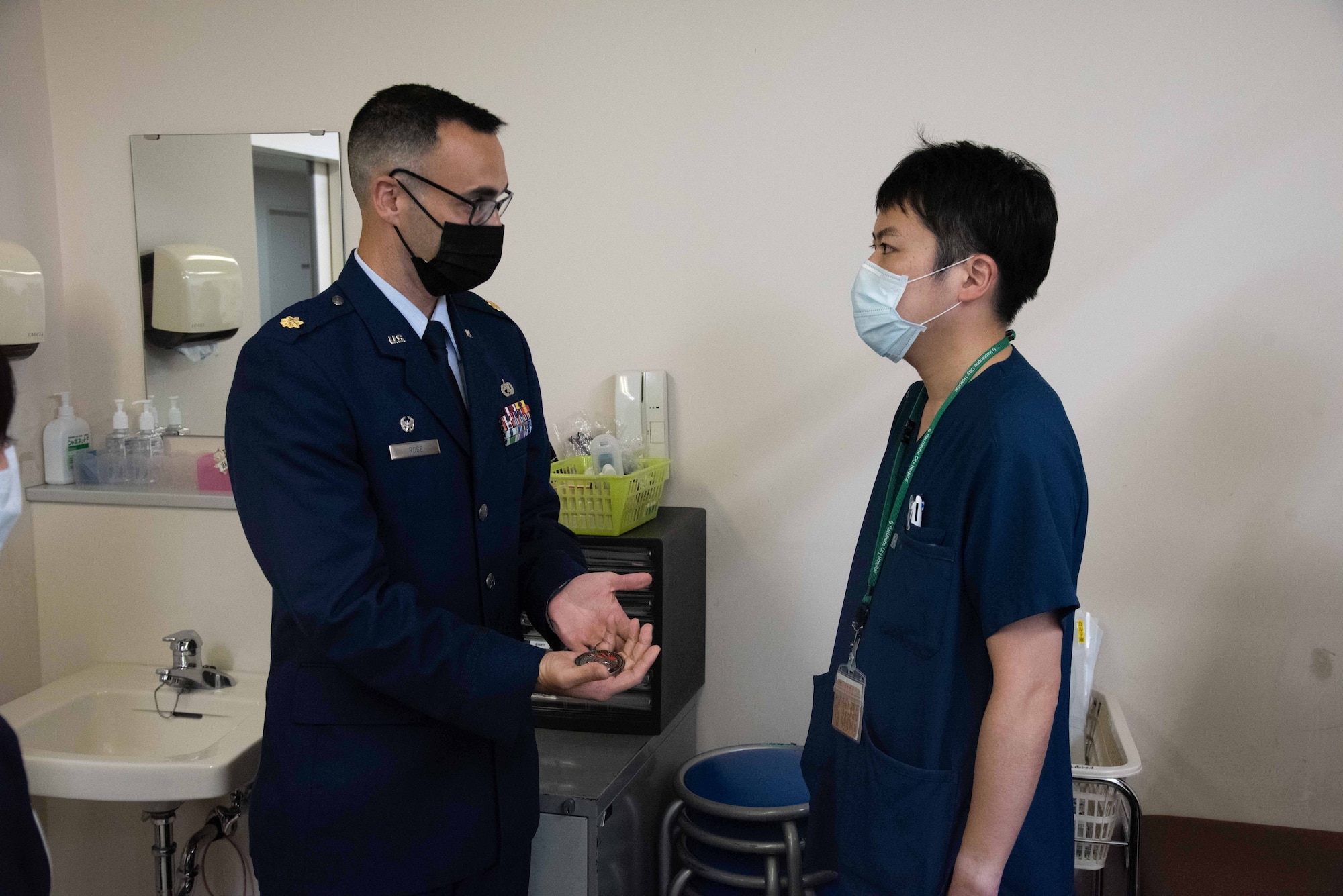 A military member explains the coin to a doctor