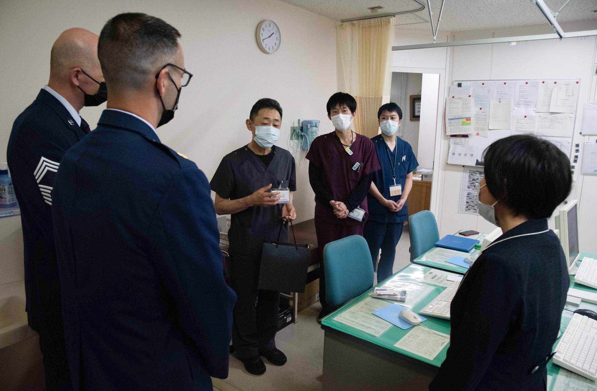 Military members listen to a doctor talk inside an office inside a hospital