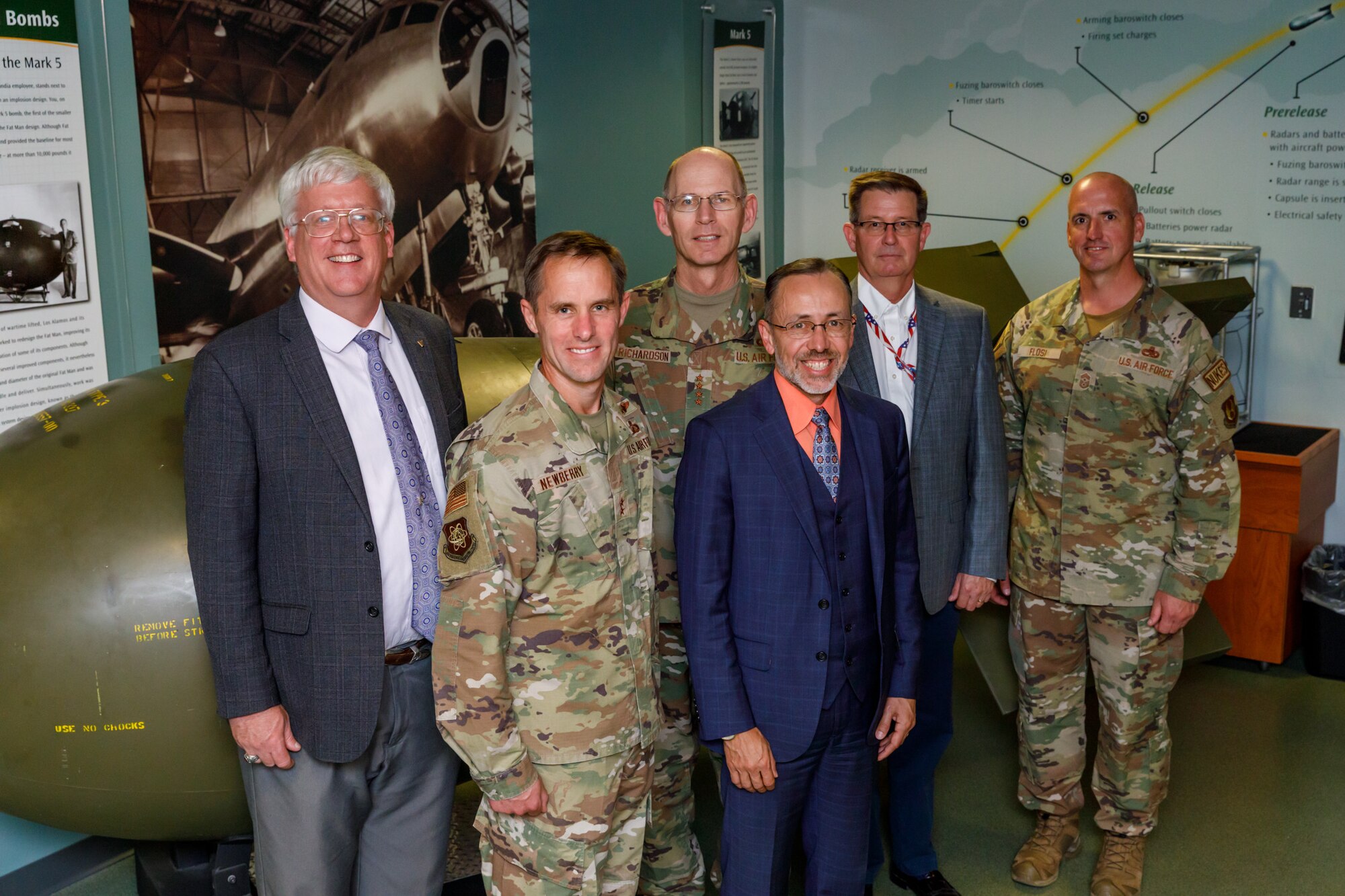 Three Airmen in uniform and three men in suits pose for a photo