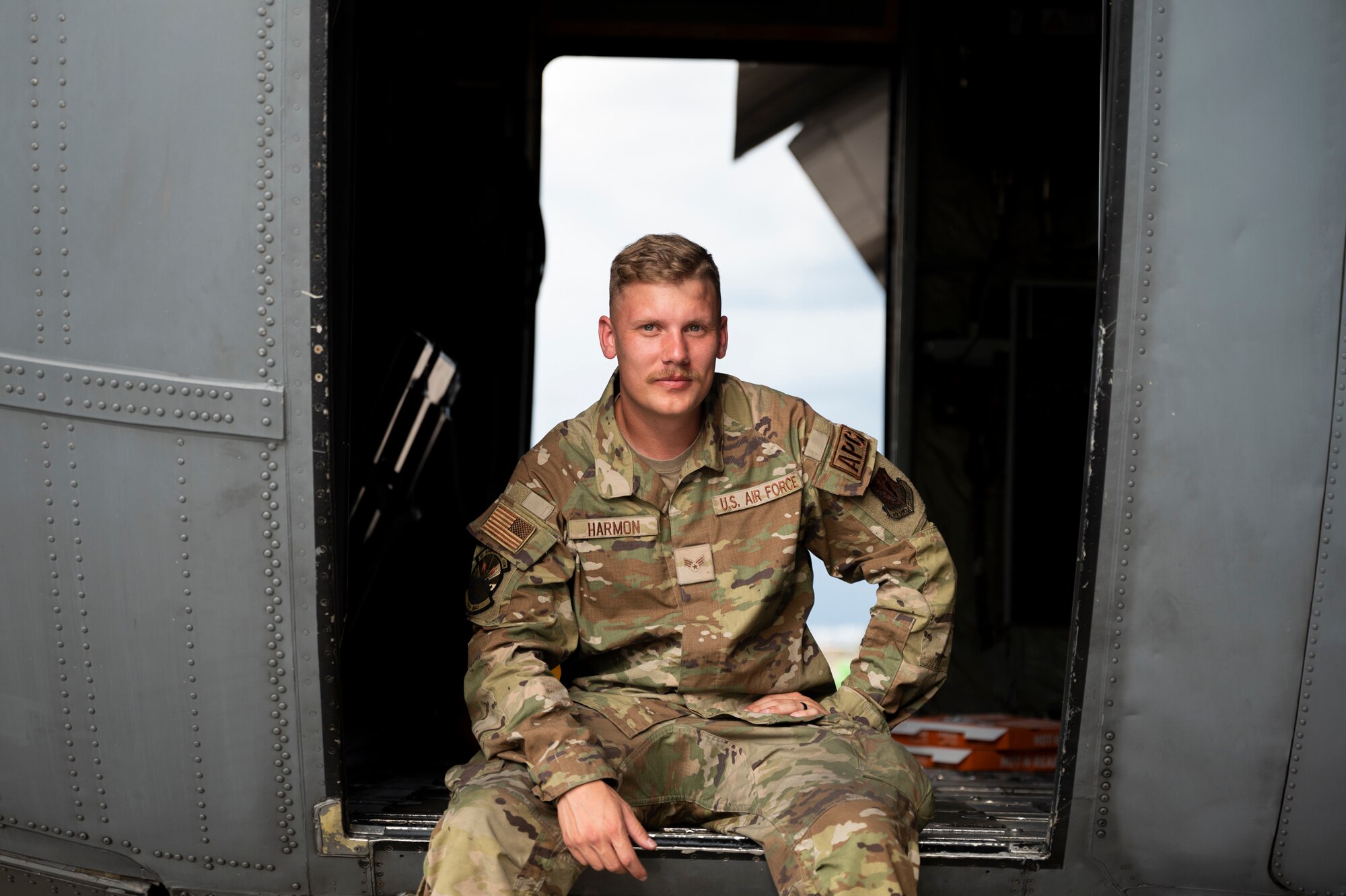 Photo of Senior Airman Harmon sitting inside the door of an EC-130H aircraft.
