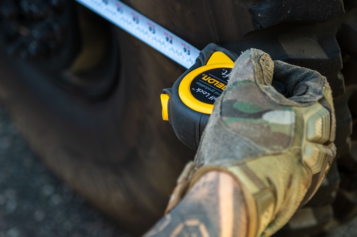 U.S. Air Force Senior Airman Enrique Arqueros, 15th Airlift Squadron air and land loadmaster, measures the tire length of a police-owned Mine Resistant Ambush Protected Vehicle, or MRAP, during a joint training exercise with the North Charleston Police Department at Joint Base Charleston, South Carolina, Sept.16, 2022. The MRAP is a six-wheeled vehicle capable of surviving gunfire of any caliber and protecting its occupants from an explosive charge. (U.S. Air Force photo by Airman 1st Class Christian Silvera)