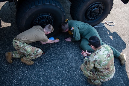 U.S. Air Force Airmen from the 15th and 16th Airlift Squadrons work together to ensure they accurately measure all sides of a tire on a police Mine Resistant Ambush Protected Vehicle (MRAP) during a joint training exercise with the North Charleston Police Department at Joint Base Charleston, South Carolina, Sept.16, 2022. The exercise prepared loadmasters to load larger vehicles onto a C-17 Globemaster III aircraft - a potential wartime scenario. (U.S. Air Force photo by Airman 1st Class Christian Silvera)