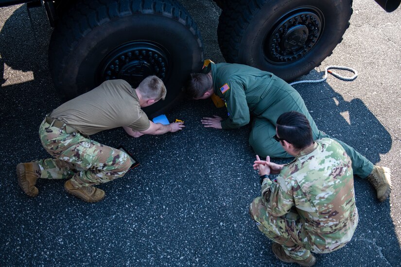 U.S. Air Force Airmen from the 15th and 16th Airlift Squadrons work together to ensure they accurately measure all sides of a tire on a police Mine Resistant Ambush Protected Vehicle (MRAP) during a joint training exercise with the North Charleston Police Department at Joint Base Charleston, South Carolina, Sept.16, 2022. The exercise prepared loadmasters to load larger vehicles onto a C-17 Globemaster III aircraft - a potential wartime scenario. (U.S. Air Force photo by Airman 1st Class Christian Silvera)