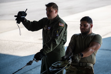 U.S. Air Force Airman 1st Class Cody Bakken, left, and Senior Airman Enrique Arqueros, right, air and land loadmasters from the 15th Airlift Squadron, pull cables from a C-17 Globemaster III during training with the North Charleston Police Department at Joint Base Charleston, South Carolina, Sept.16, 2022. The exercise prepared loadmasters to load larger vehicles onto a C-17 Globemaster III aircraft - a potential wartime scenario. (U.S. Air Force photo by Airman 1st Class Christian Silvera)