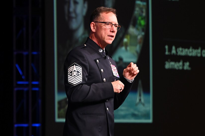 A military officer speaks from a stage.
