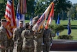 man in u.s. army uniform holding flag passes it to woman in uniform.