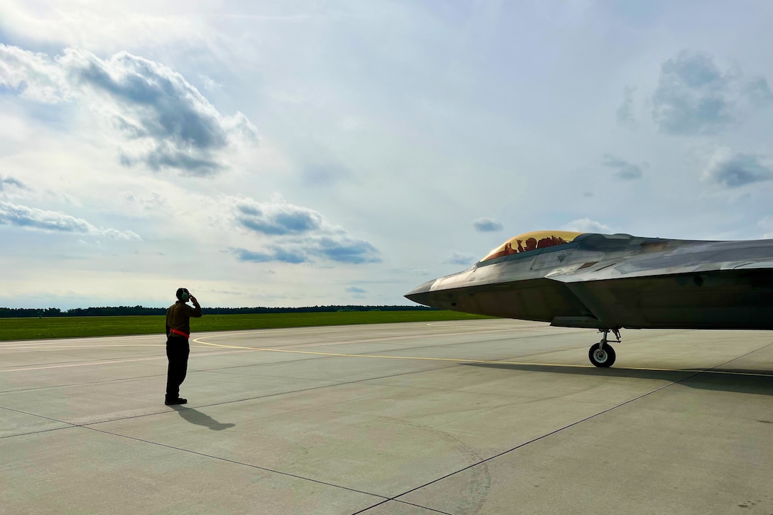 An airman salutes a pilot in a jet.