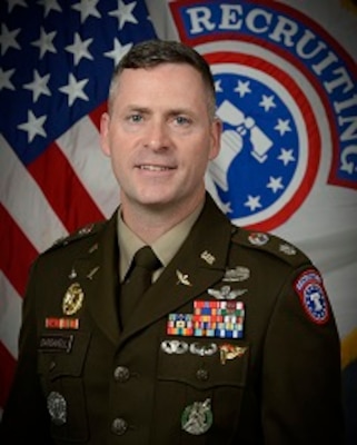 man wearing u.s. army uniform standing in front of 2 flags
