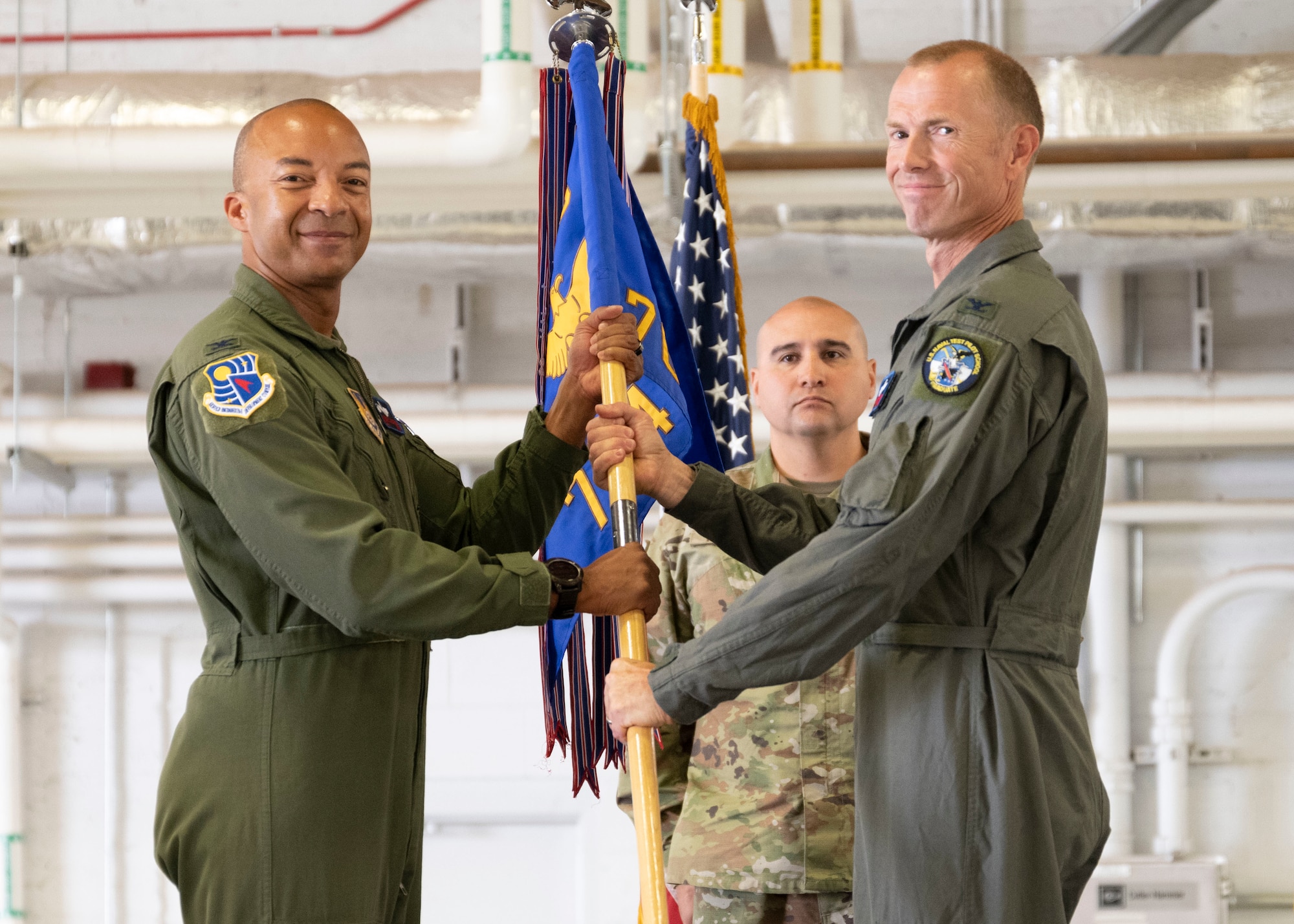 Col. Randel Gordon, commander, Arnold Engineering Development Complex, passes the guidon to Col. Karl Seekamp. Both men are smiling and looking at the camera.