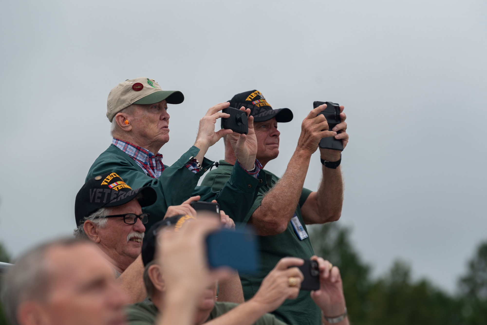 Audience members record video footage during a combat search and rescue demonstration at Moody Air Force Base, Georgia, Sept. 9, 2022. Air Rescue Association members, who were once a part of the rescue community, watched the demonstration and attended a ceremony to celebrate the HH-60W Jolly Green II meeting the criteria for initial operational capability and being postured for declaration. (U.S. Air Force photo by Senior Airman Jasmine M. Barnes)