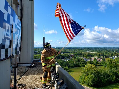 A firefighter from the 788th Civil Engineer Squadron plants an American flag at the top of the building 620 tower on Wright-Patterson Air Force Base, Ohio, Sept. 12, 2022, to begin the 9/11 memorial stair climb. The Air Force Research Laboratory held this memorial event to commemorate the victims and first responders of the 9/11 terrorist attacks. (Courtesy photo)
