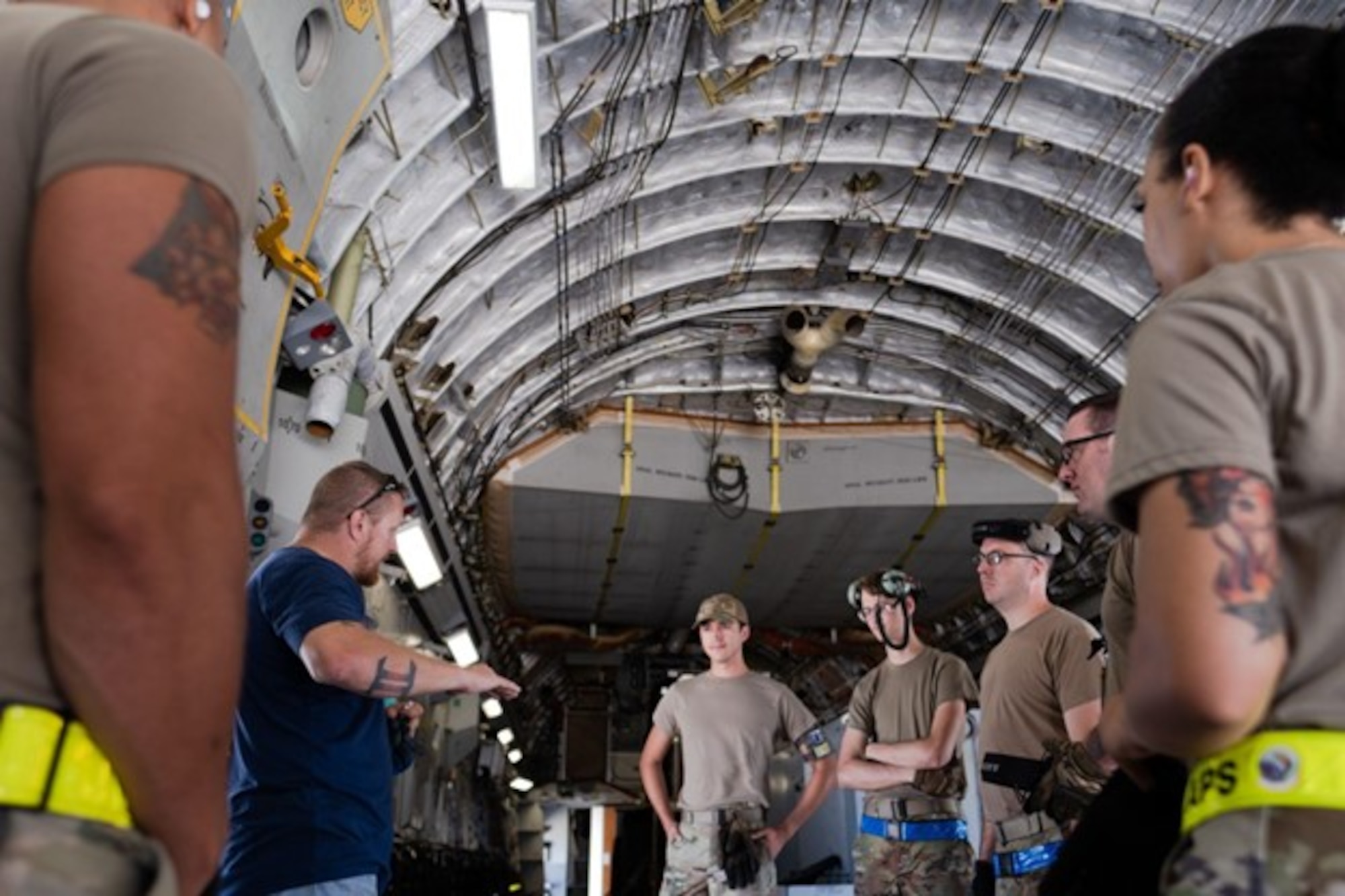 Man speaks to group of airmen inside C-17