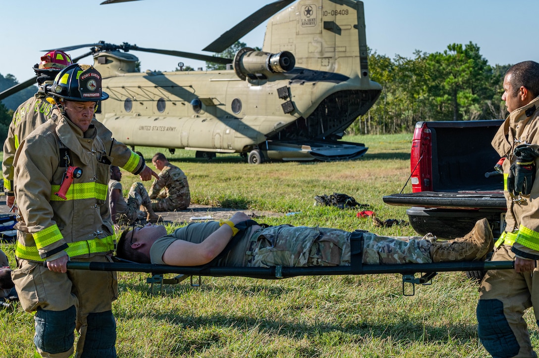 Jason Winters (left) and Joseph Cook, firefighters with Fort Eustis Fire and Emergency Services, carry simulated victim on a stretcher for evacuation during the aircraft down exercise at Joint Base Langley-Eustis, Virginia, Sept. 20, 2022.