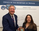 man and woman in business suits hold award