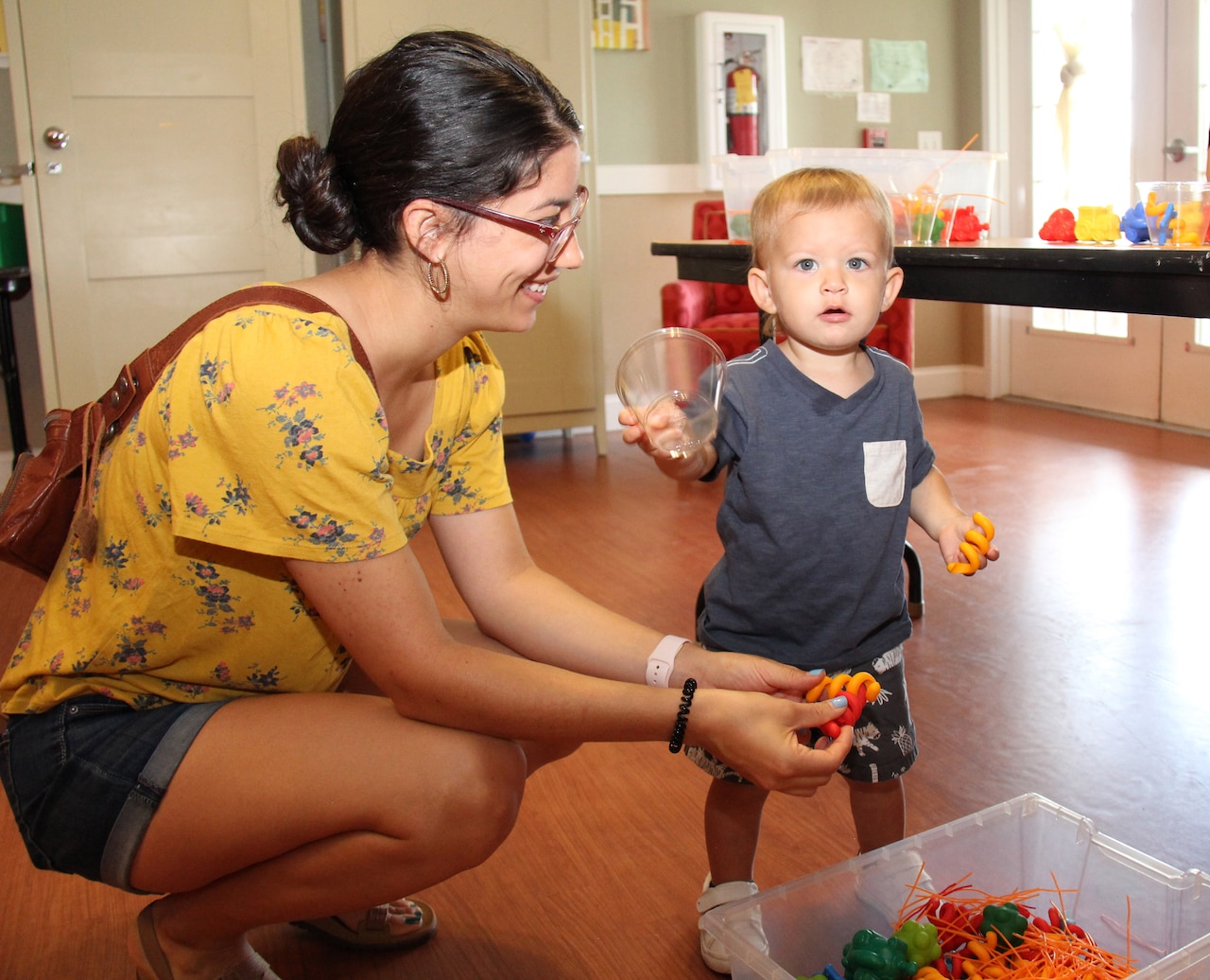 A woman kneels near a small child.