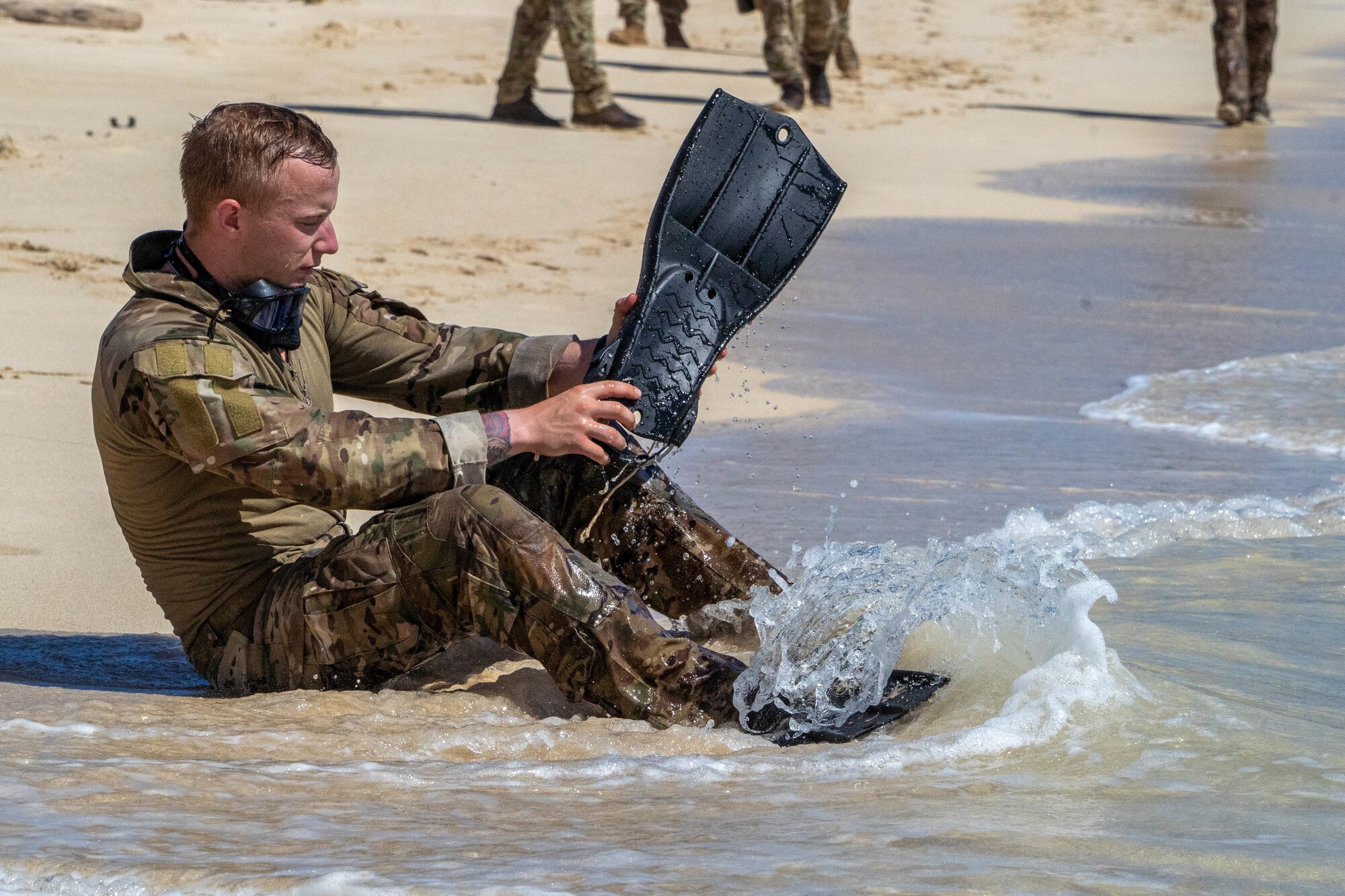 U.S. Air Force Senior Airman Mason Egan, 5th Air Support Operations Squadron tactical air control party specialist, party specialist, dons fins to prepare for a one-mile open water swim to finish Chaos Challenge 2022 at Bellows Air Station, Aug. 15, 2022. The Chaos Challenge is an annual competition highlighting Pacific Air Forces top two-person TACP teams while completing mentally and physically challenging events revolving around field skills, land navigation, close air support skills and a wide spectrum of job knowledge task evaluations. (U.S. Air Force photo by Senior Airman Makensie Cooper)