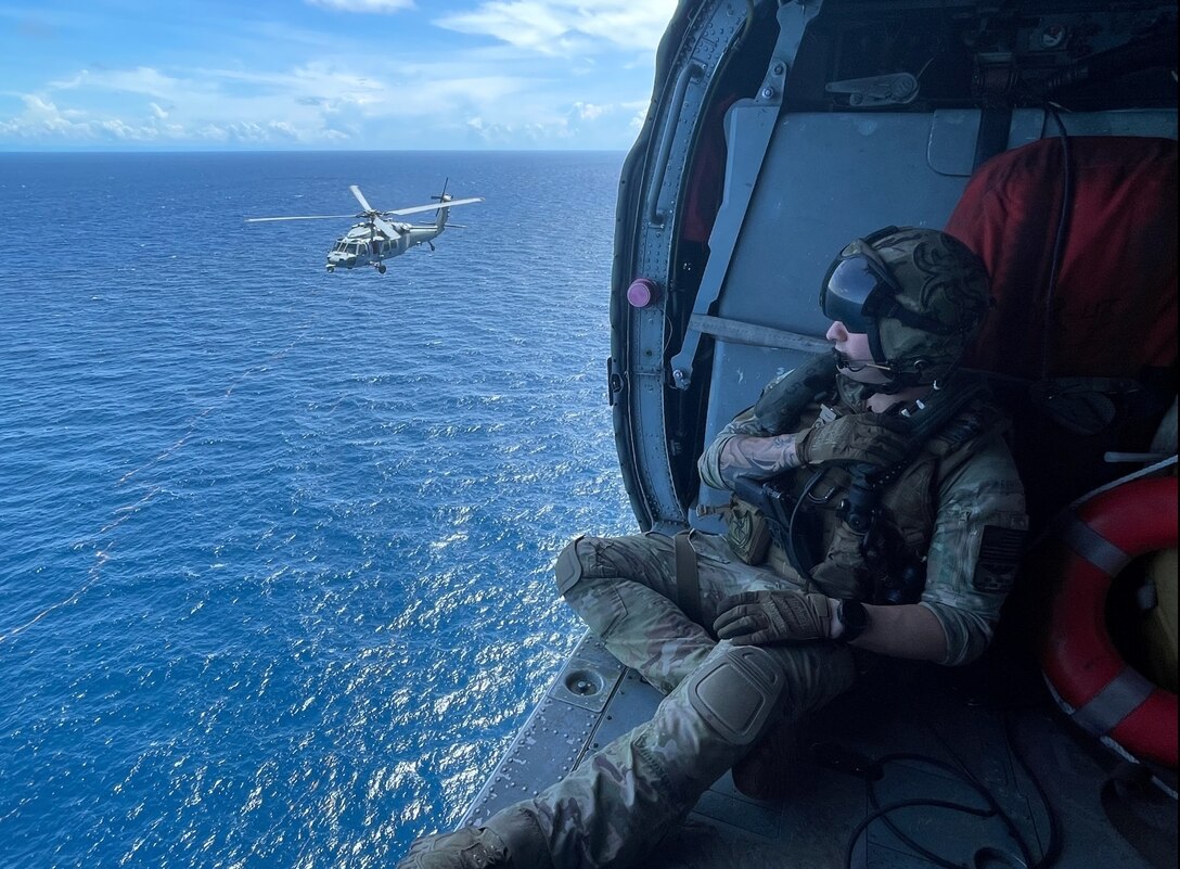 Naval Aircrewman (Helicopter) 1st Class Benjamin Chellew assigned to Helicopter Sea Combat Squadron (HSC) 28, Detachment 8, overlooks an MH-60s Sea Hawk helicopter assigned to HSC-28, Detachment 6, during a photo exercise in the Caribbean Sea, Sept. 10, 2022. Wichita and Billings are deployed to the U.S. 4th Fleet area of operations to support Joint Interagency Task Force South’s mission, which includes counter-illicit drug trafficking missions in the Caribbean and Eastern Pacific