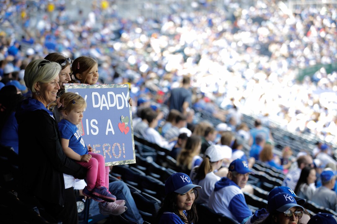 A family holds a sign while in the seats at a stadium.