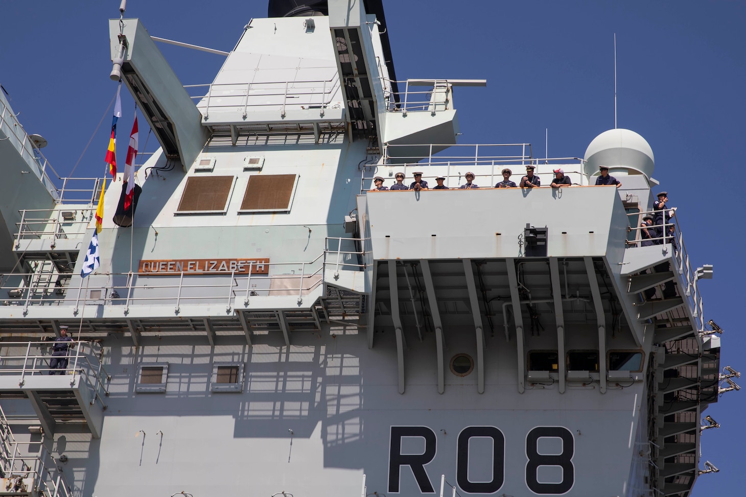 British Sailors watch from the British Royal Navy aircraft carrier HMS Queen Elizabeth (RO8) as the ship ports at Pier 12 in Naval Station Norfolk